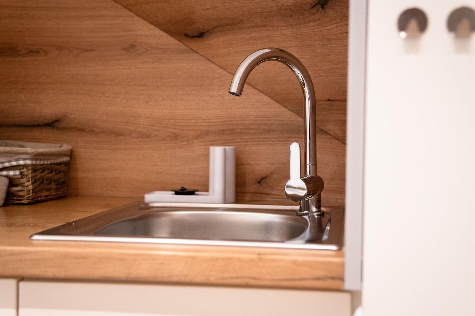 Küchenarmatur mit Edelstahlbecken und Holzrückwand