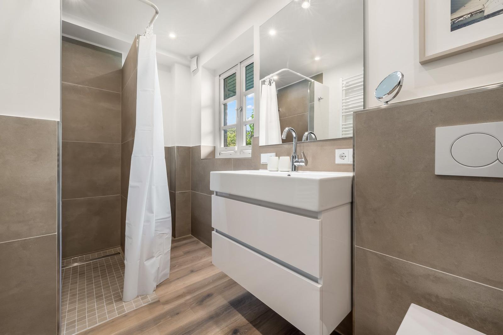 Badezimmer mit Dusche, Waschbecken und Fenster