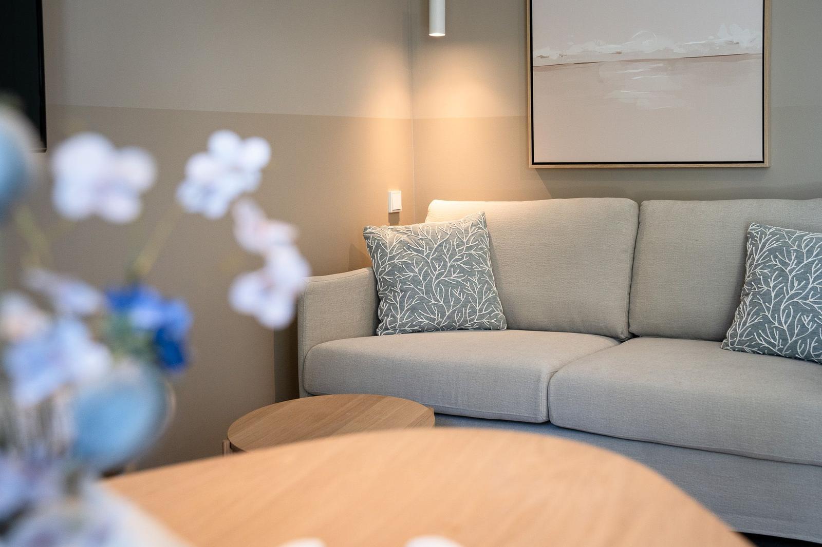 Ein grauer Sofa mit zwei Kissen und einem Bild an der Wand.