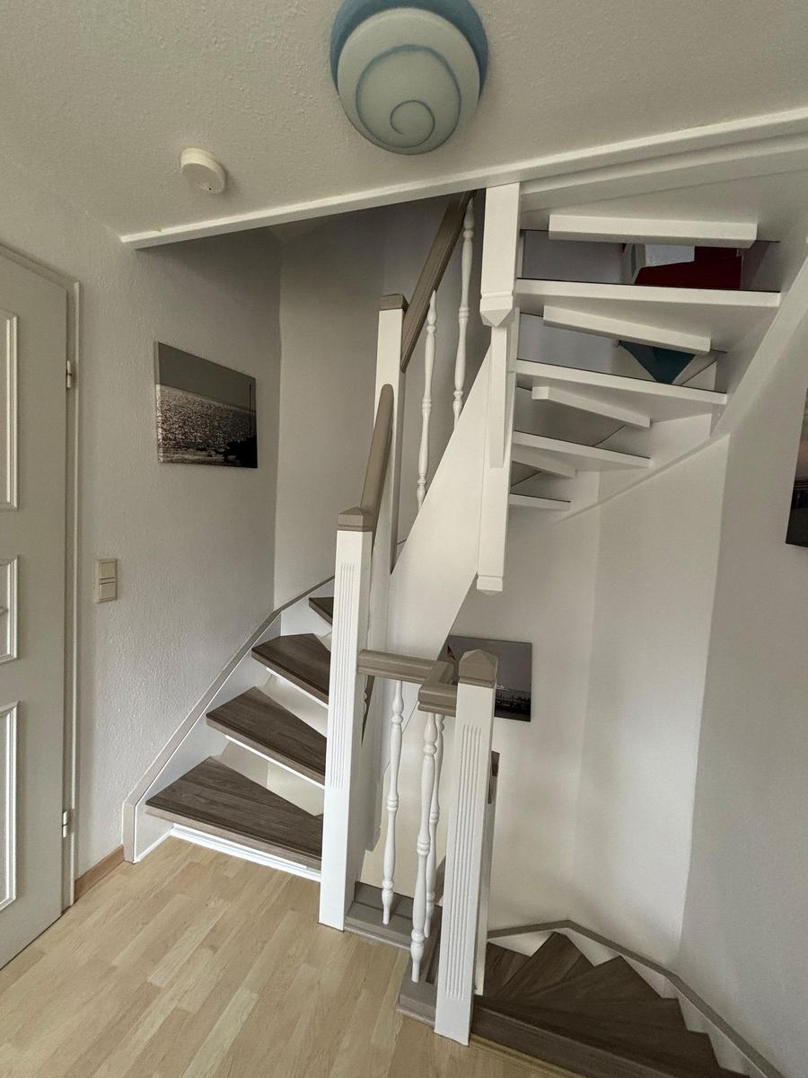 Haus mit Treppe zur oberen Etage. Holzstufen und weiße Geländer.