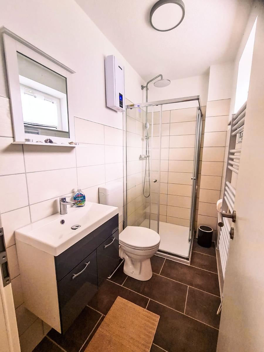Badezimmer mit Dusche, Toilette und Waschbecken mit Spiegel.