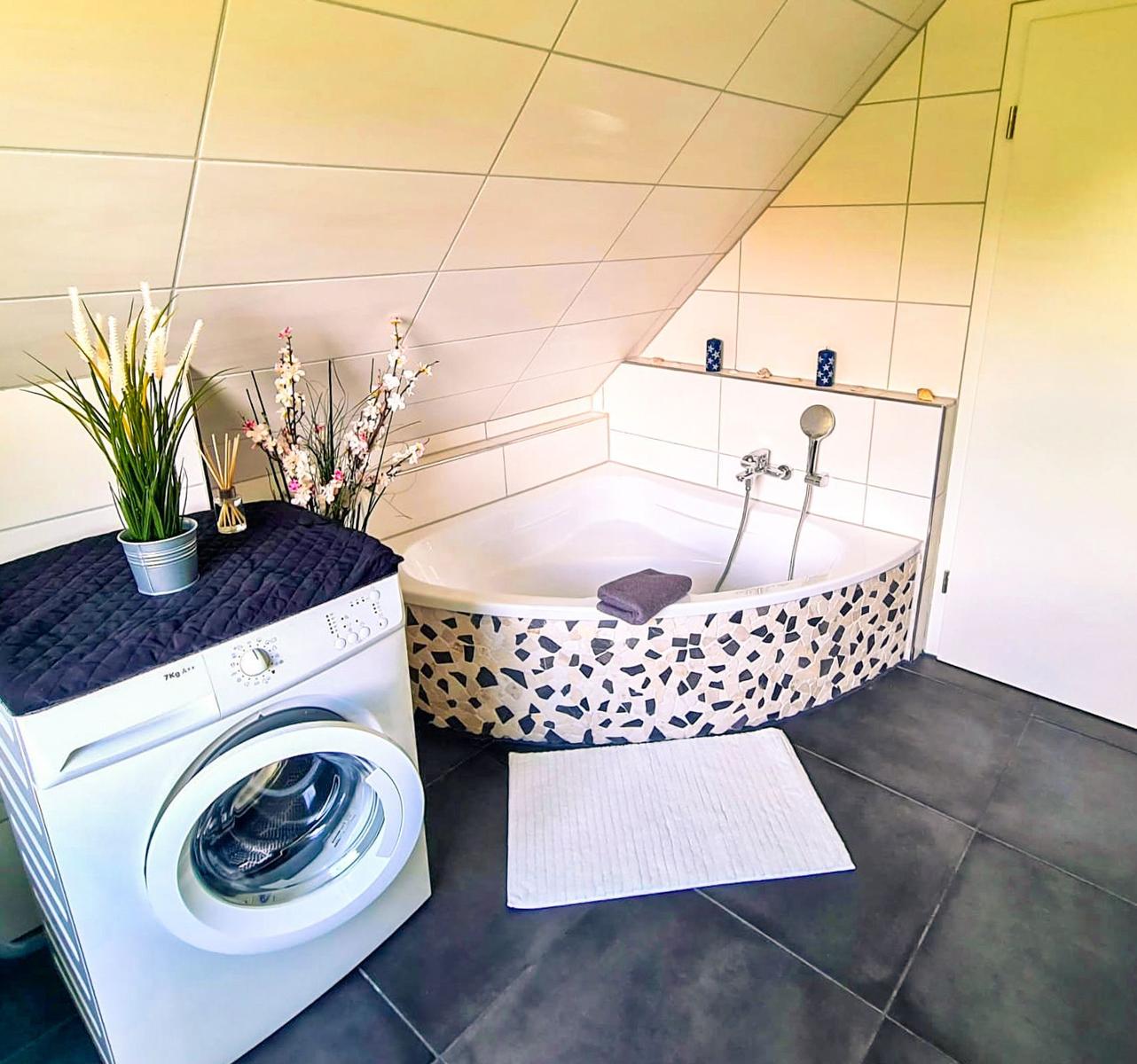 Badezimmer mit Dusche, Waschmaschine und Mosaikbadewanne