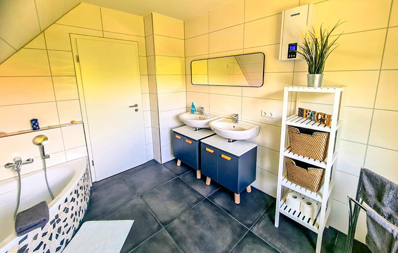 Badezimmer mit Dusche, zwei Waschbecken und einem Regal mit Körben.