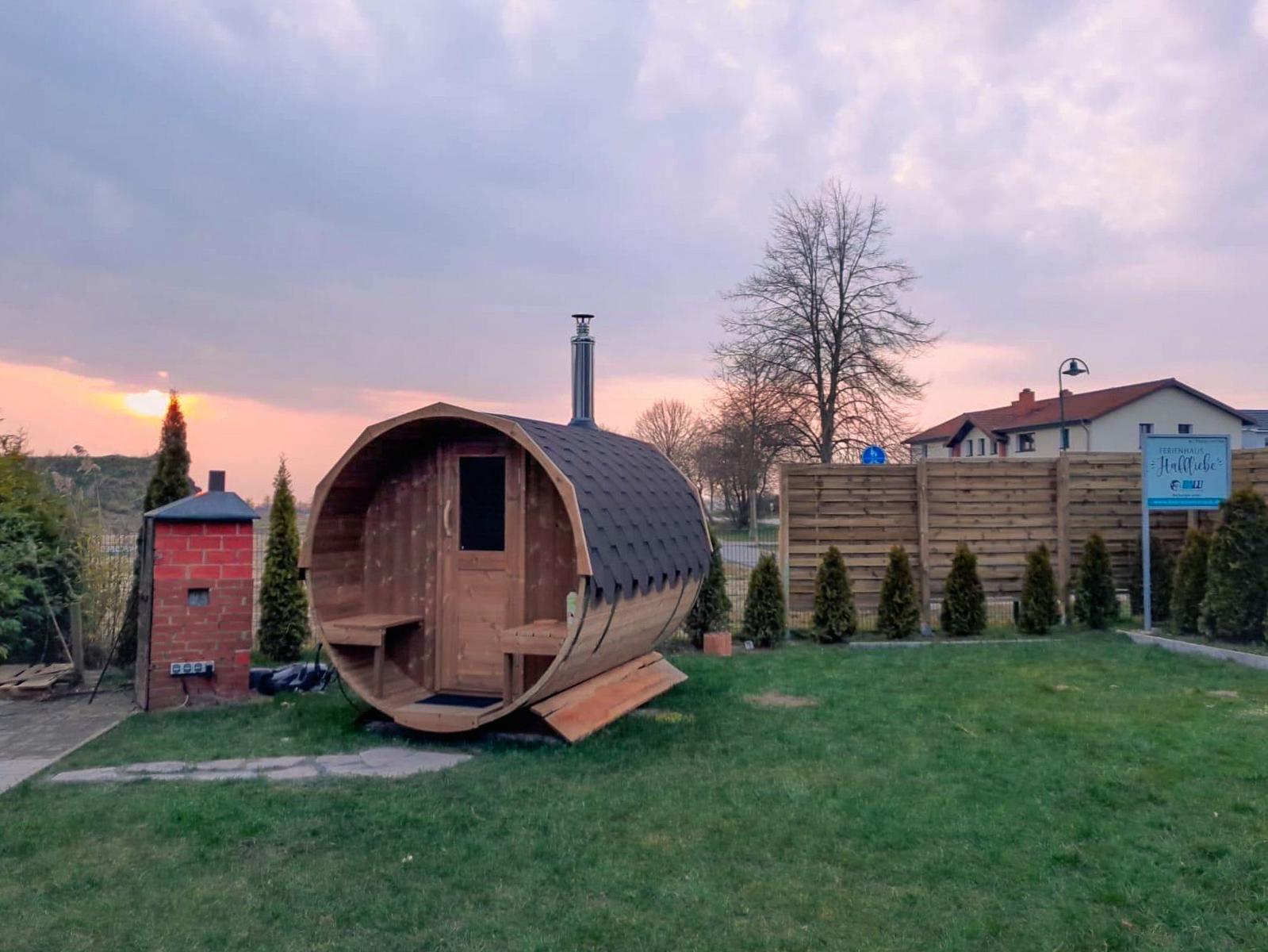 Holzsauna im Garten mit Grill und Sitzbank.