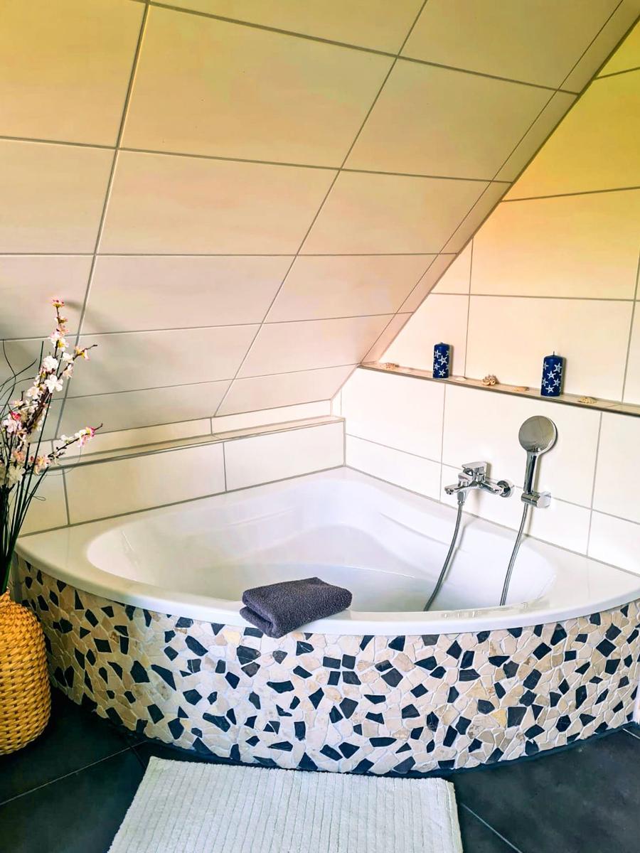 Dusche mit Mosaikfliesen und Duschbrause in einem Badezimmer mit geneigtem Dach