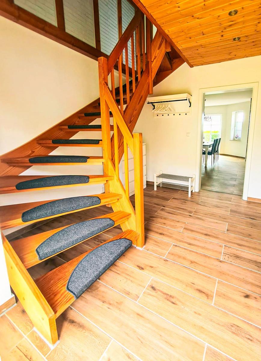 Holztreppe mit grauen Stufen führt zur oberen Etage. Holzfußboden und Decke.