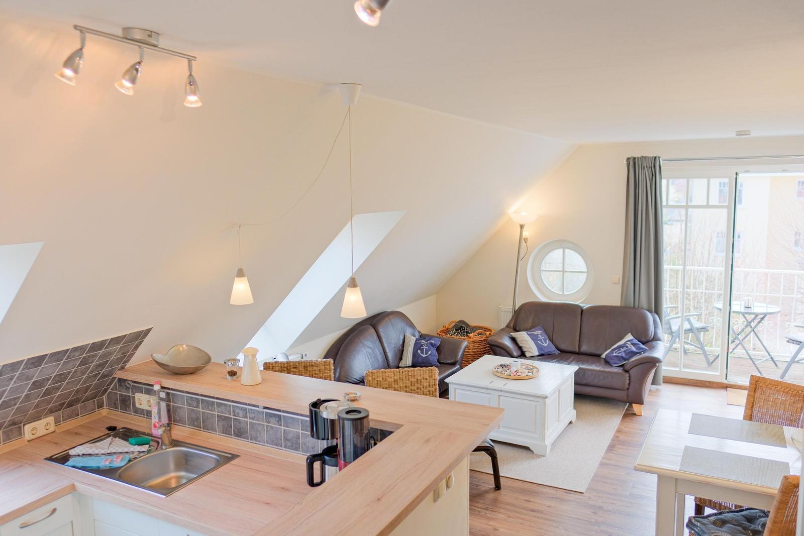 Wohnküche mit Sofa, Esstisch und Balkonzugang.