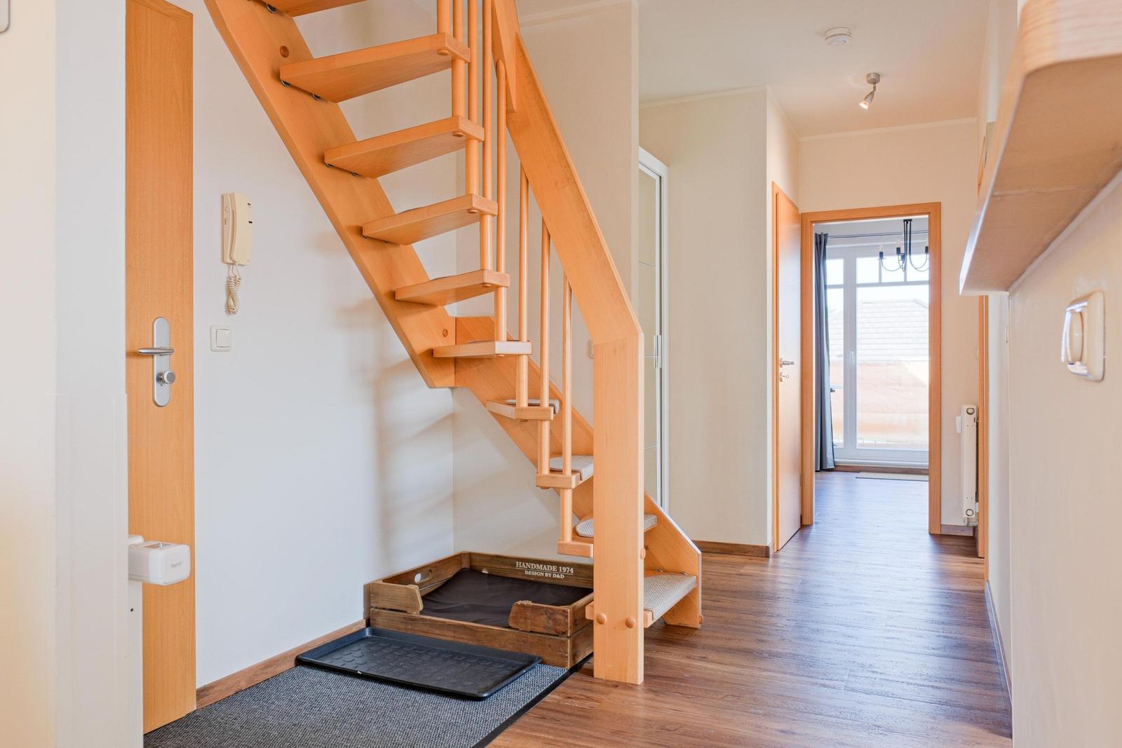 Holztreppe führt zur oberen Etage. Unterstufe mit Hundebett. Holzfußboden und Türen.