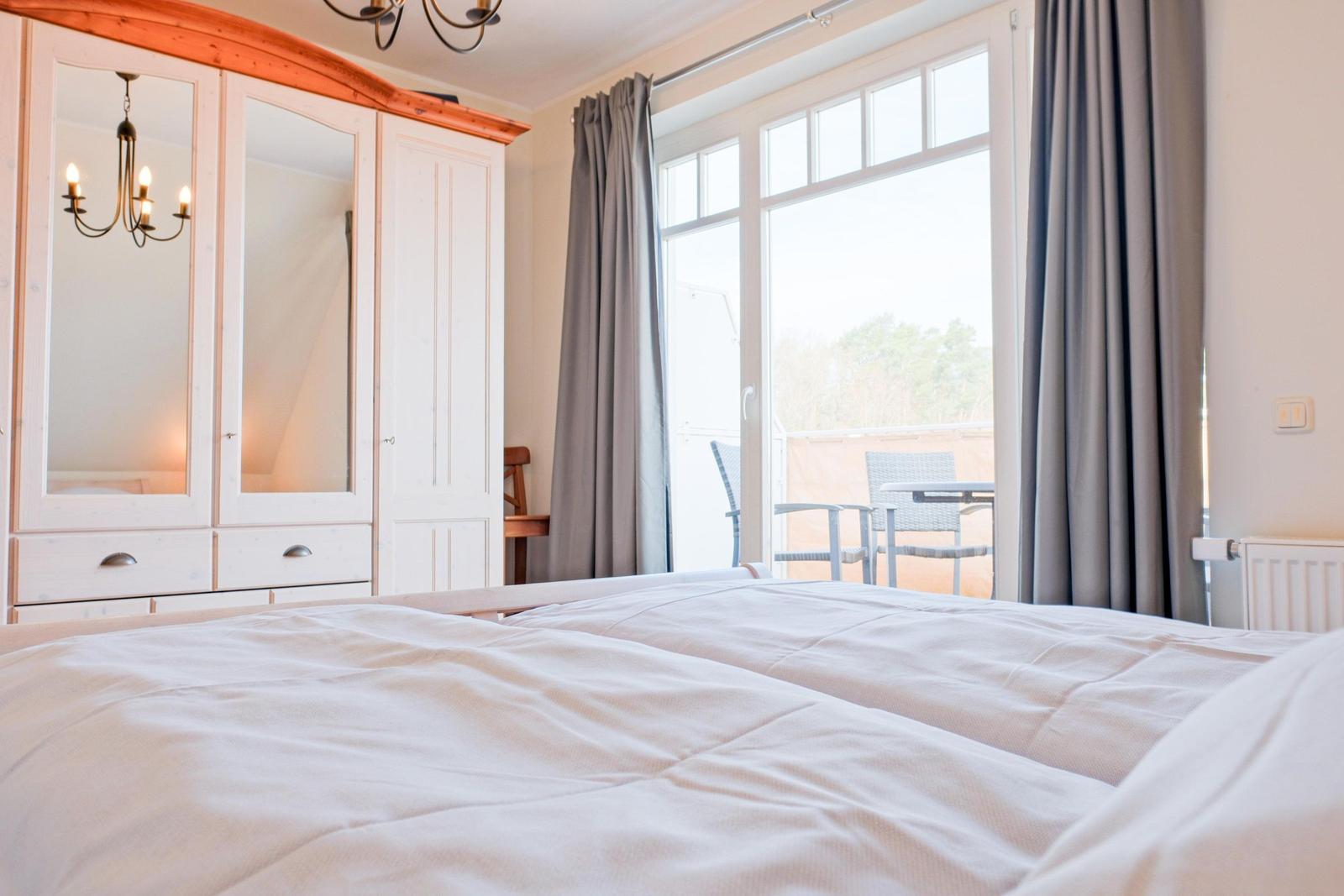 Schlafzimmer mit Doppelbett, Schrank und Balkonansicht.