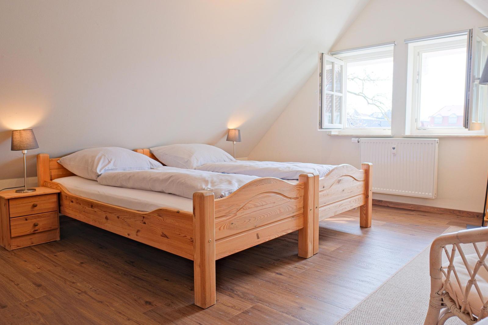 Schlafzimmer mit Holzbett, Nachttischen und Fenstern