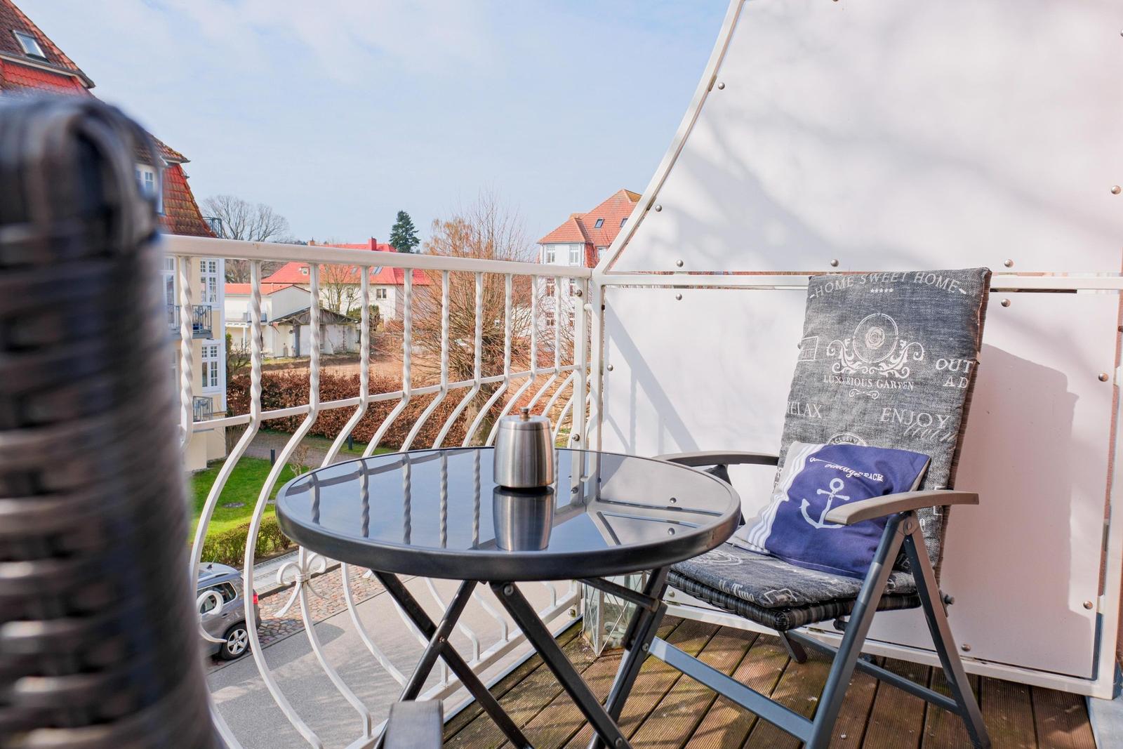 Terrasse mit Stuhl, Tisch und Sicht auf die Straße und Häuser.