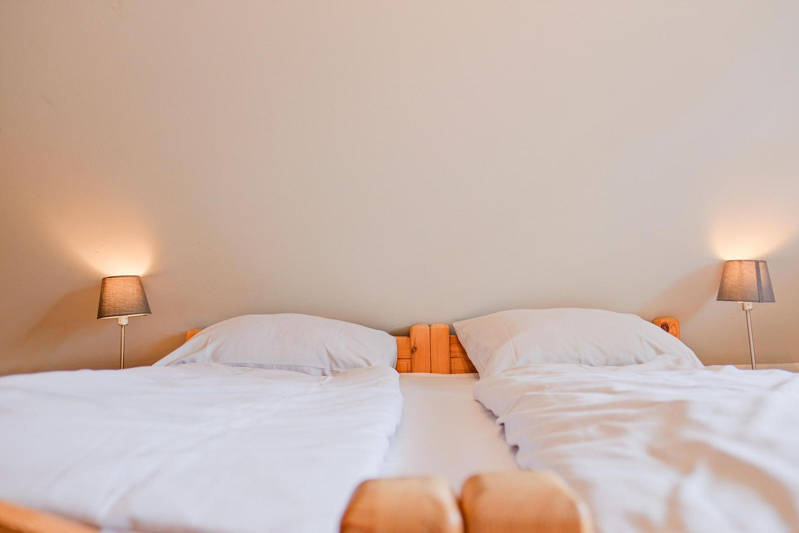 Ein Bett mit weißer Bettwäsche und zwei Nachttischlampen an der Wand.