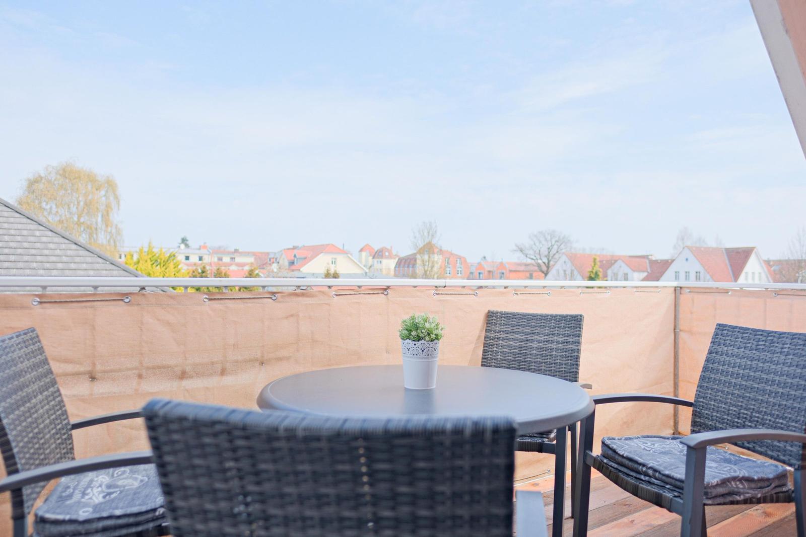Terrasse mit Tisch und Stühlen, Blick auf Wohngebiet.
