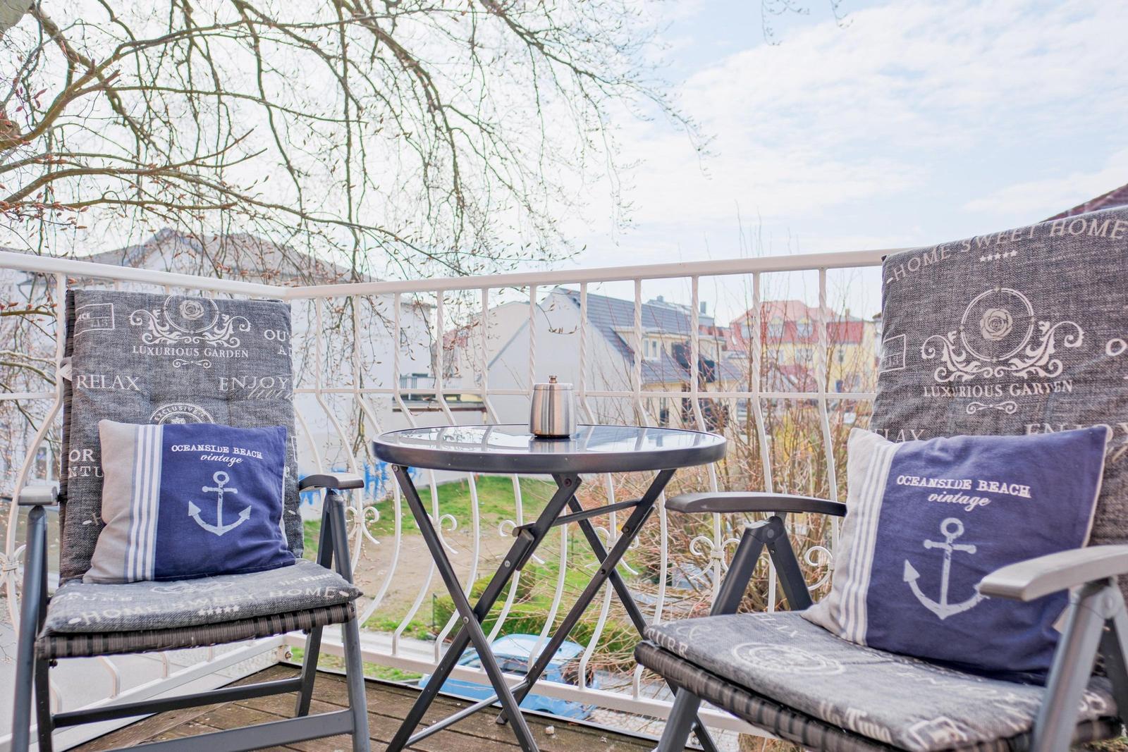 Terrasse mit zwei Stühlen, Tisch und Blick auf Wohnhäuser.