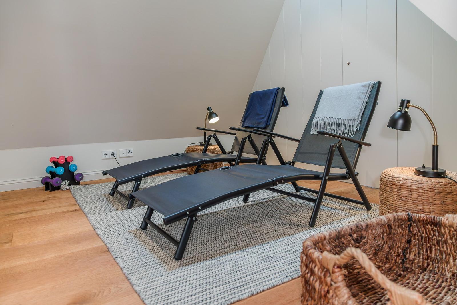 Zwei Liegestühle mit Decken, Lampen und Körben auf Holzboden mit Teppich.