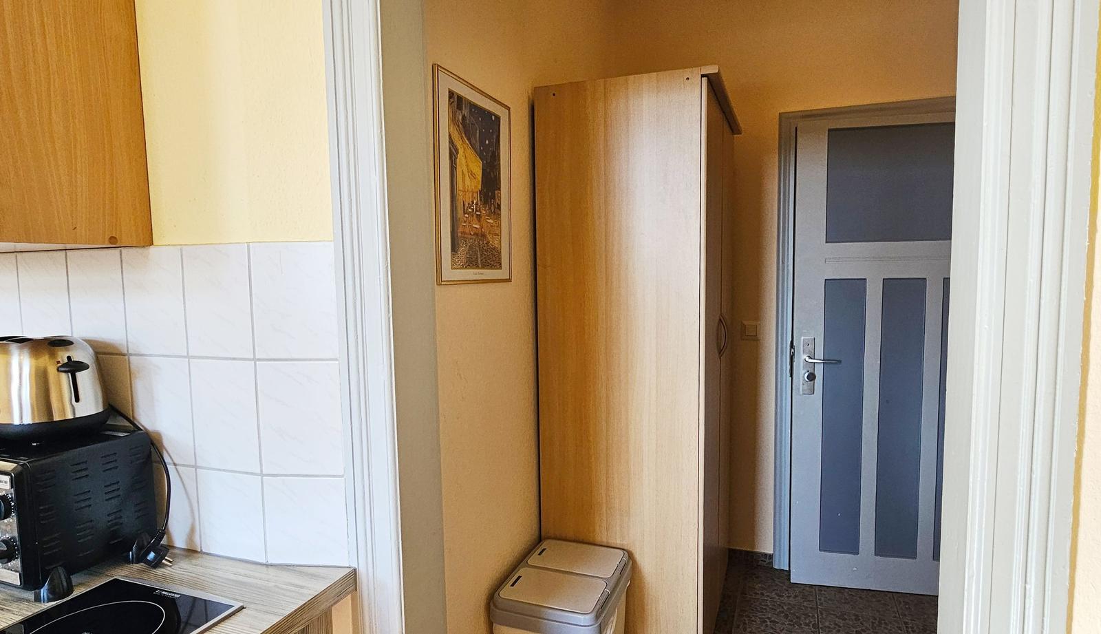 Küche mit Toaster und Kühlschrank, daneben Schrank und Tür