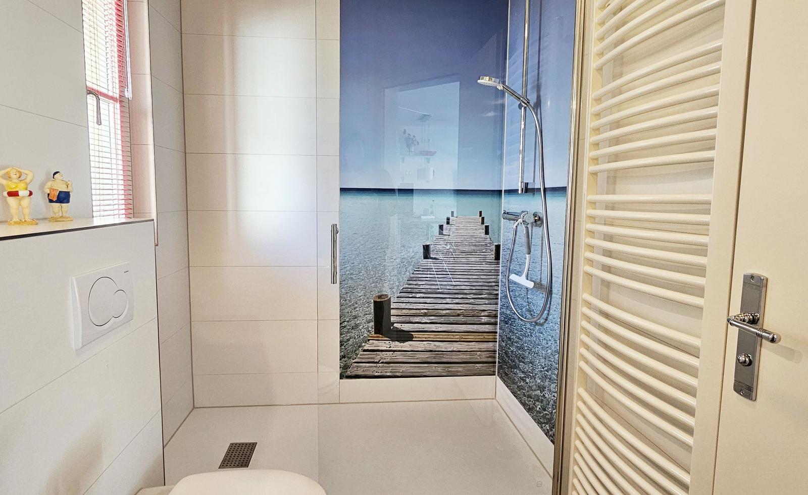 Duschkabine mit Strandmotiv, Toilette und Heizkörper