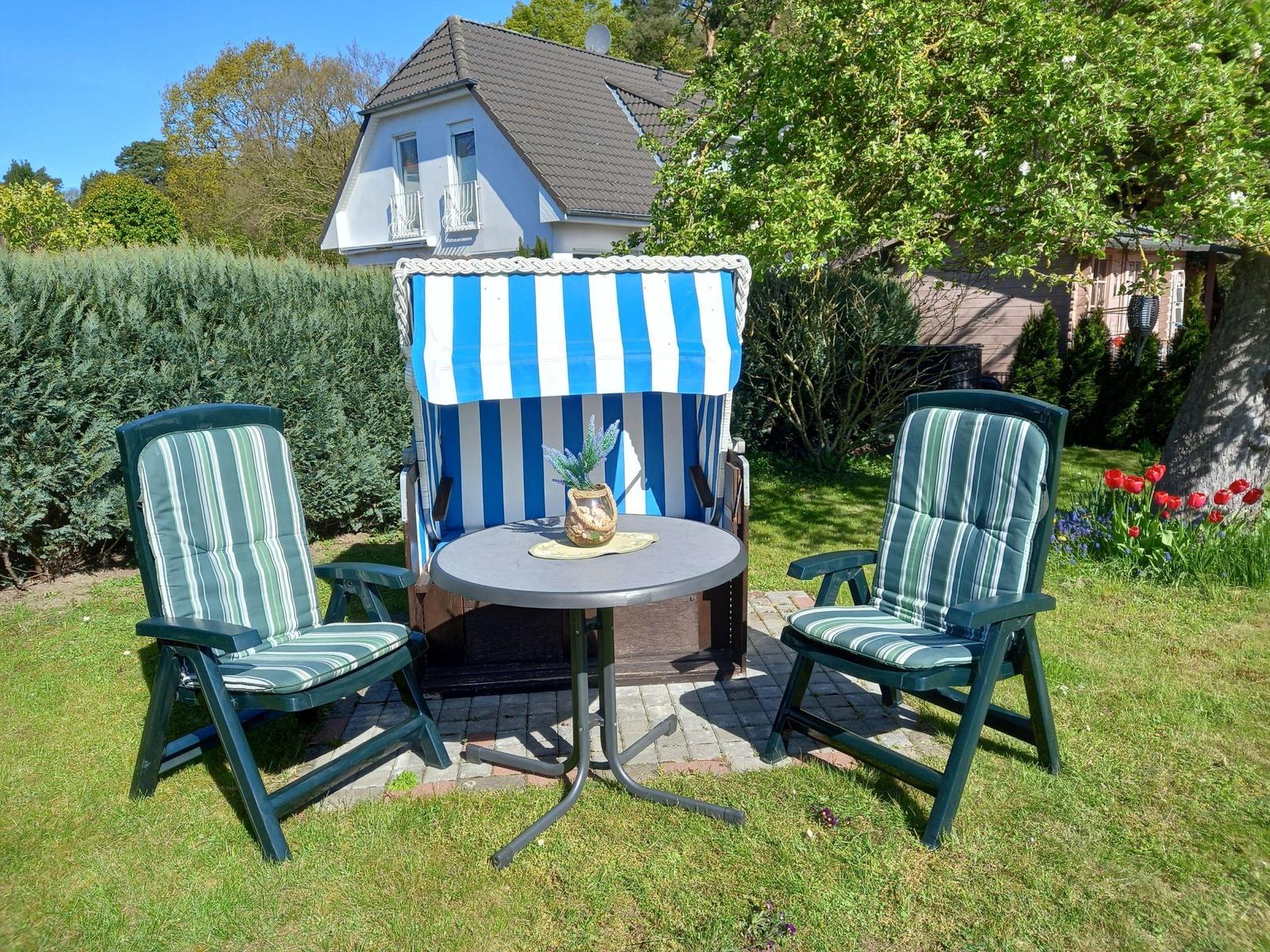 Terrasse mit zwei Stühlen, Tisch und Strandkorb im Garten.