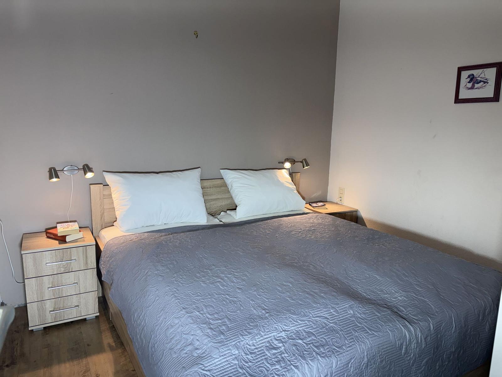 Schlafzimmer mit Bett, zwei Nachttischen und Wandbild