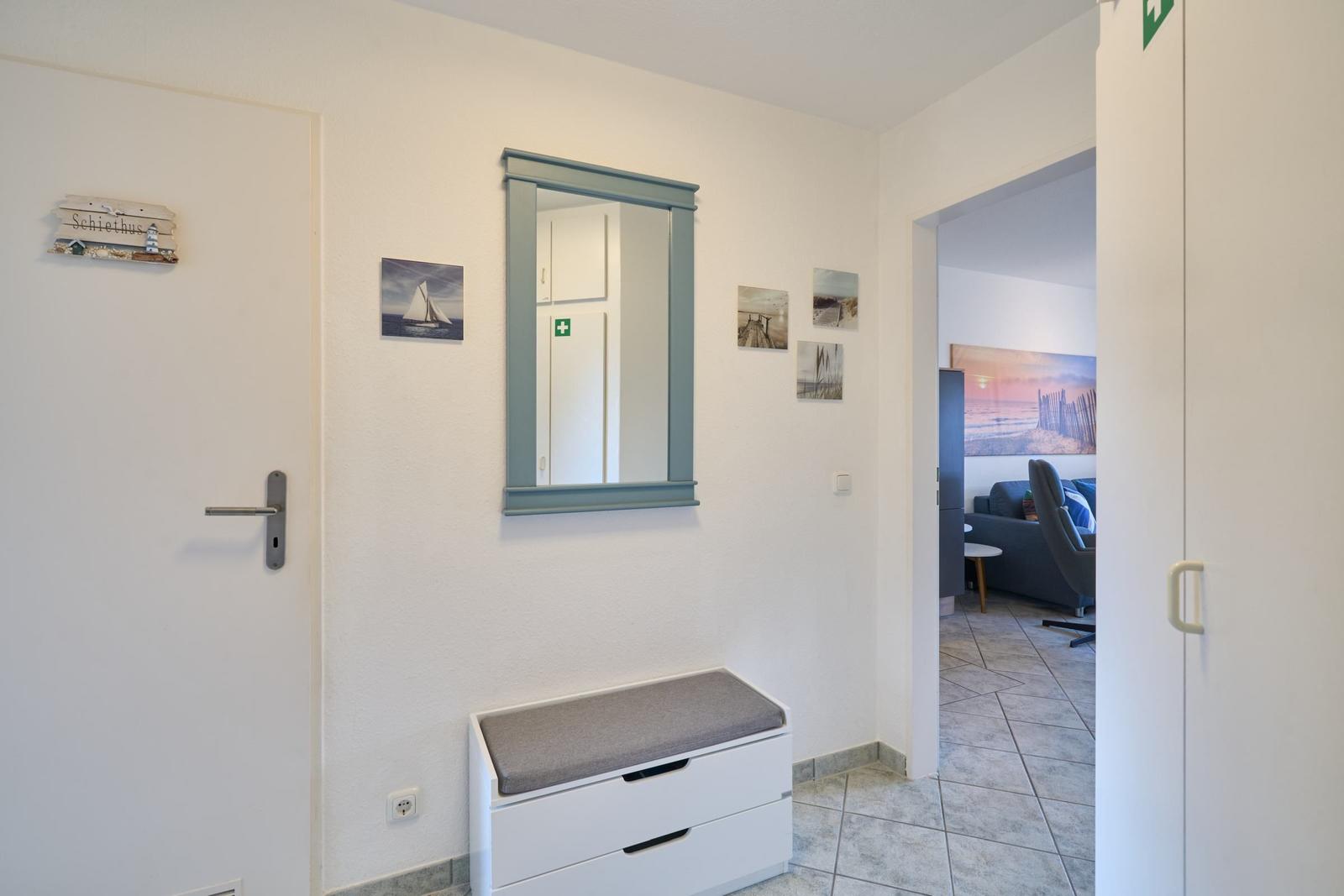 Eingangsbereich mit Spiegelschrank, Sitzbank und Blick ins Wohnzimmer.