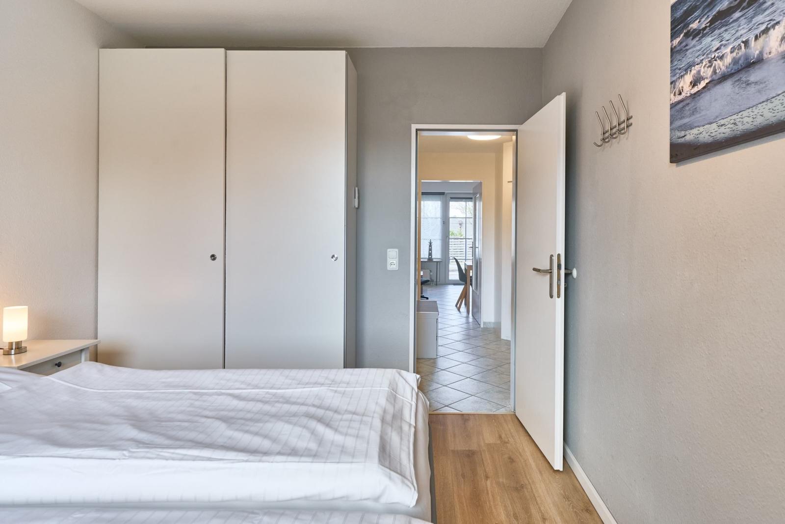 Schlafzimmer mit Bett, Kleiderschrank und Tür zum Flur.