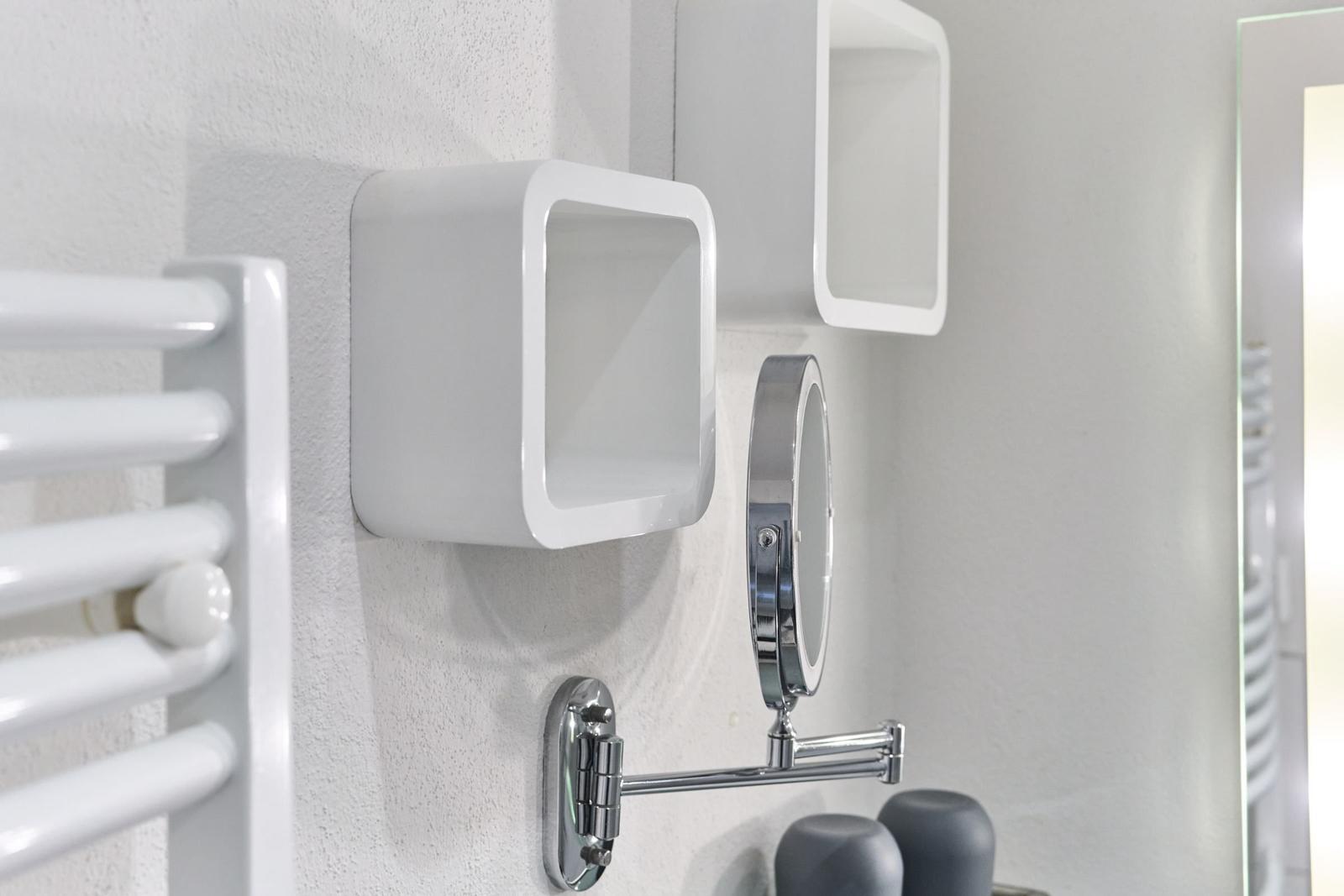 Badezimmer mit weißen Wandregalen, Spiegel und Heizkörper.