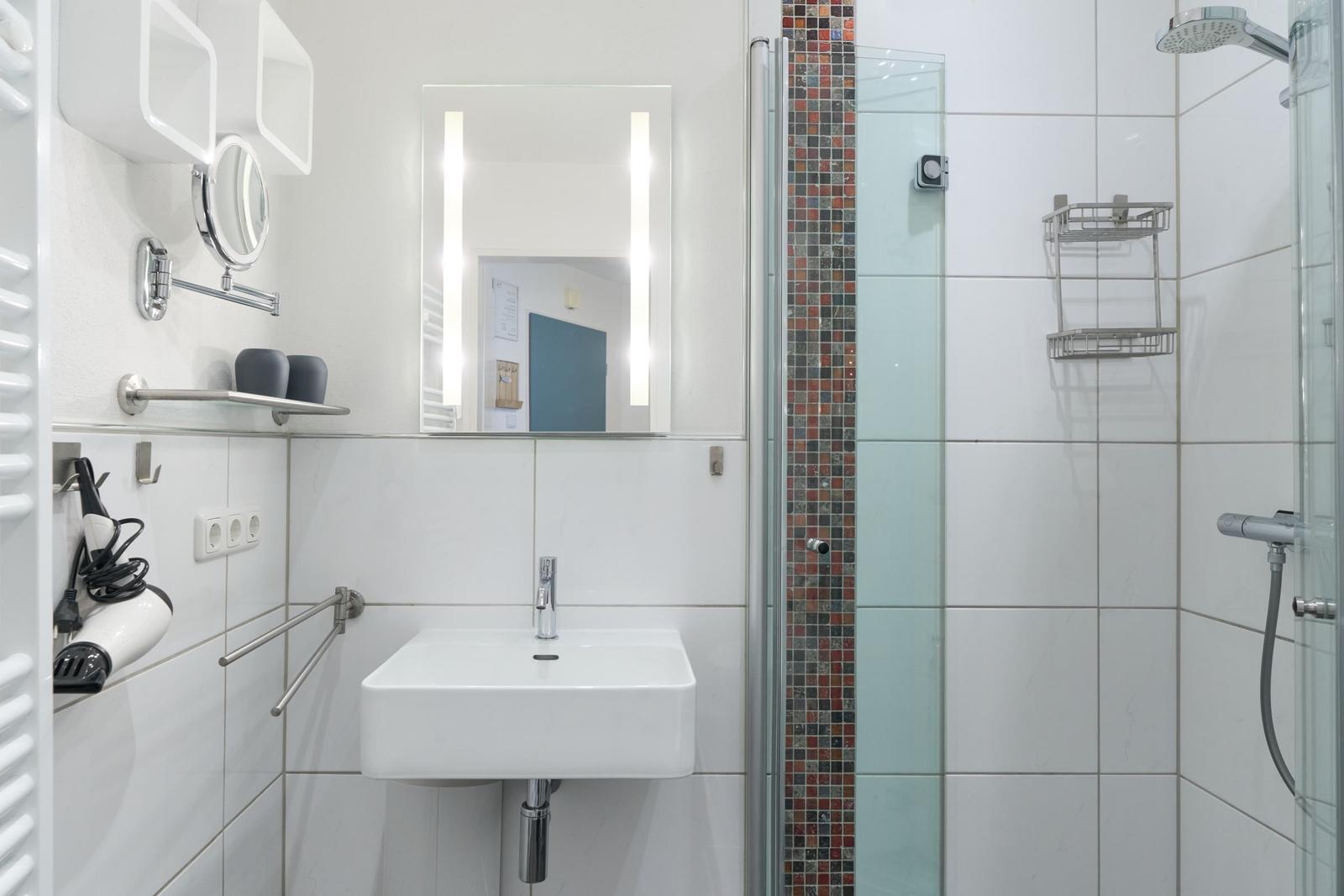 Badezimmer mit Dusche, Waschbecken und Spiegel