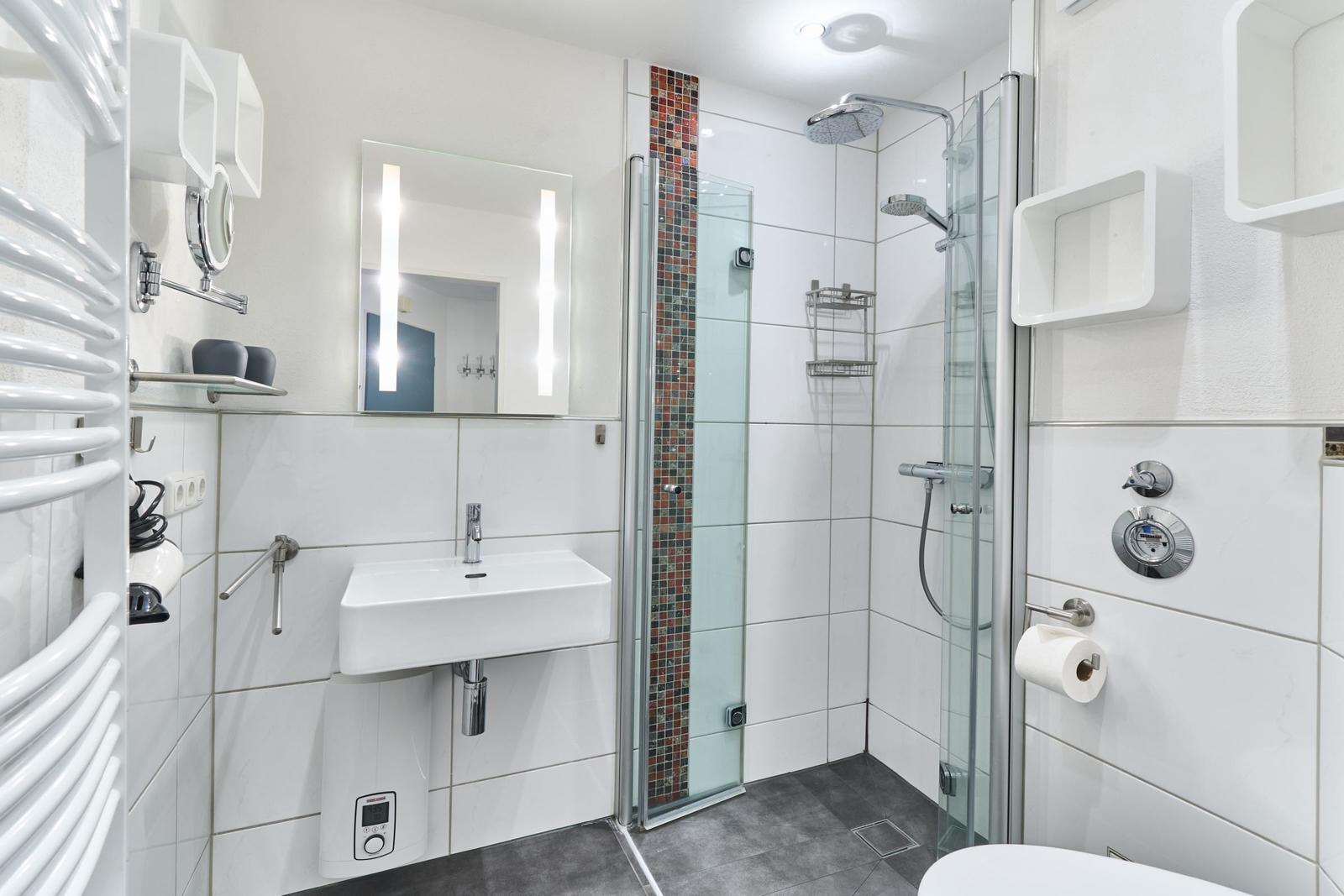 Badezimmer mit Dusche, Waschbecken und Heizkörper