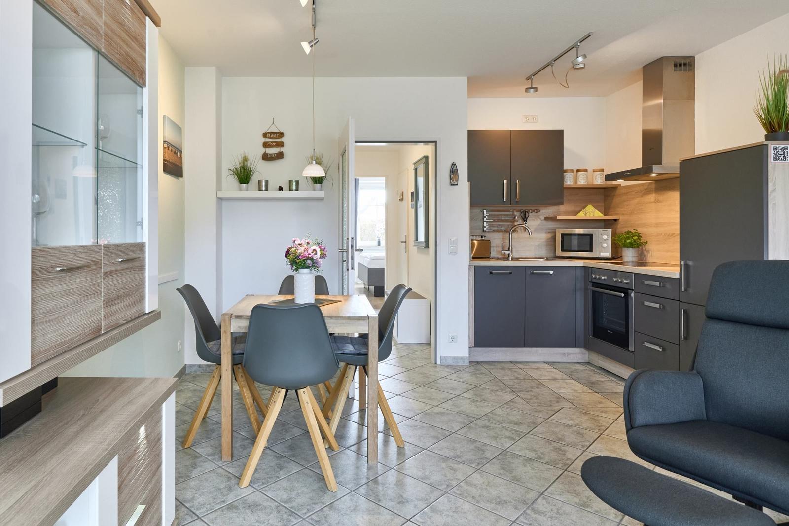 Küche mit Essbereich und Sitzgelegenheit. Holztisch, graue Stühle und moderne Einrichtung.