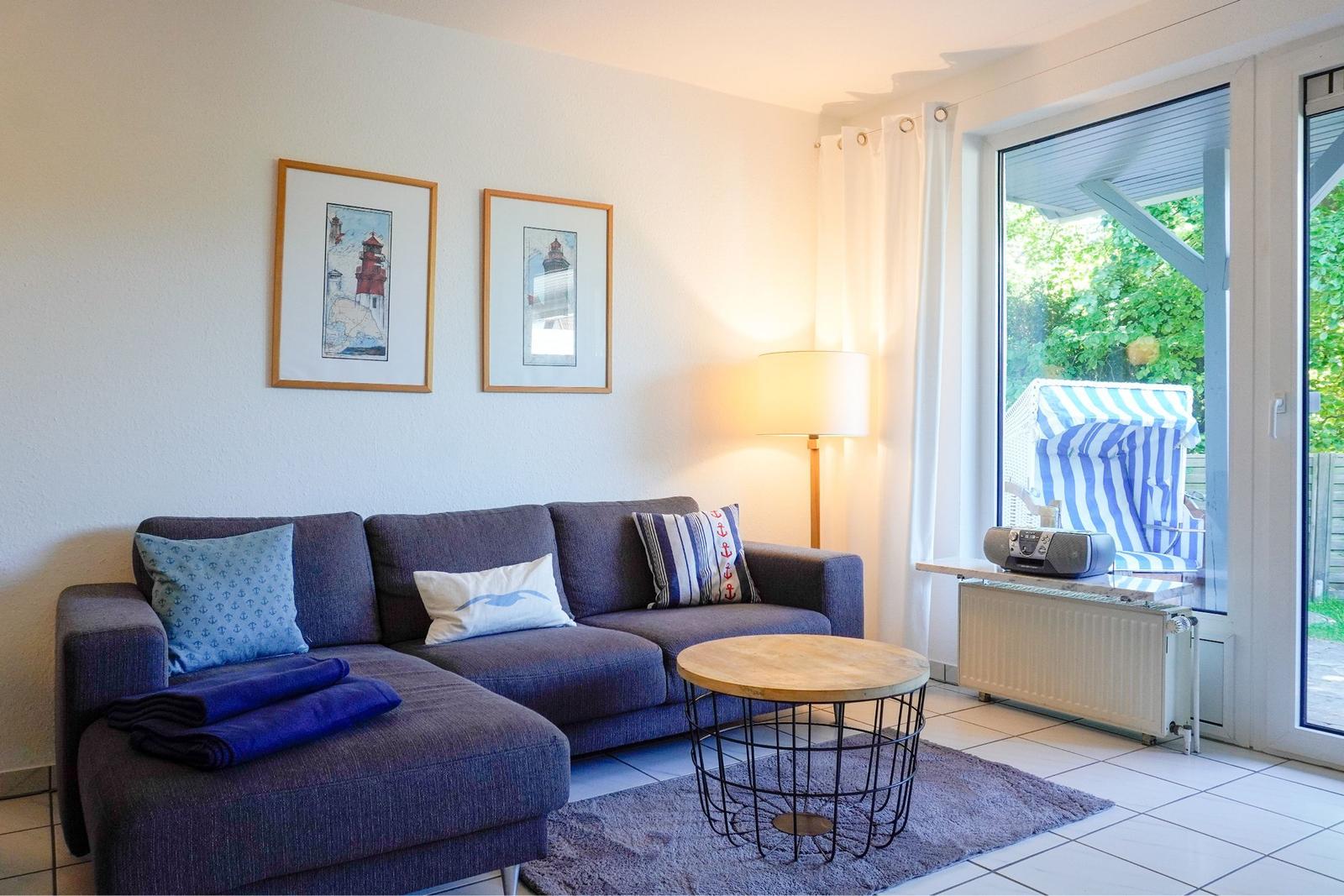 Ein Wohnzimmer mit Sofa, Tisch und Blick auf einen Strandkorb.