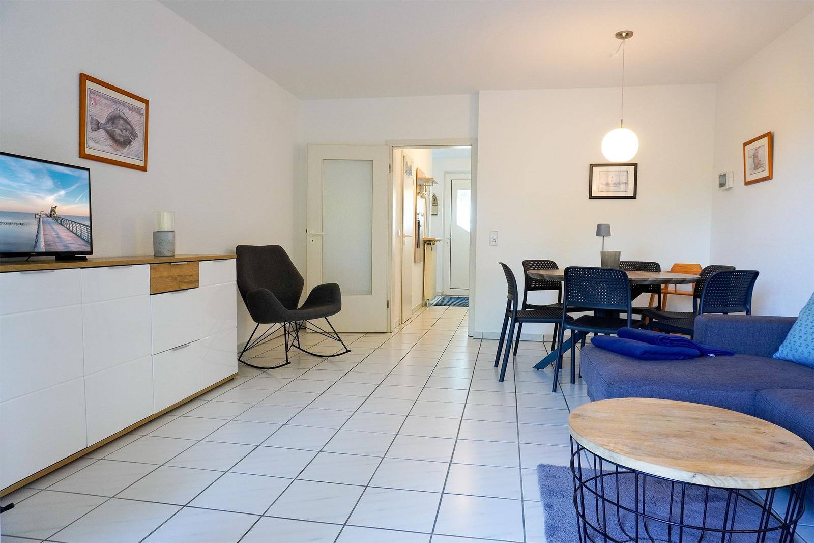 Wohn- und Essbereich mit Sofa, Tisch, Stühlen und Fernseher.