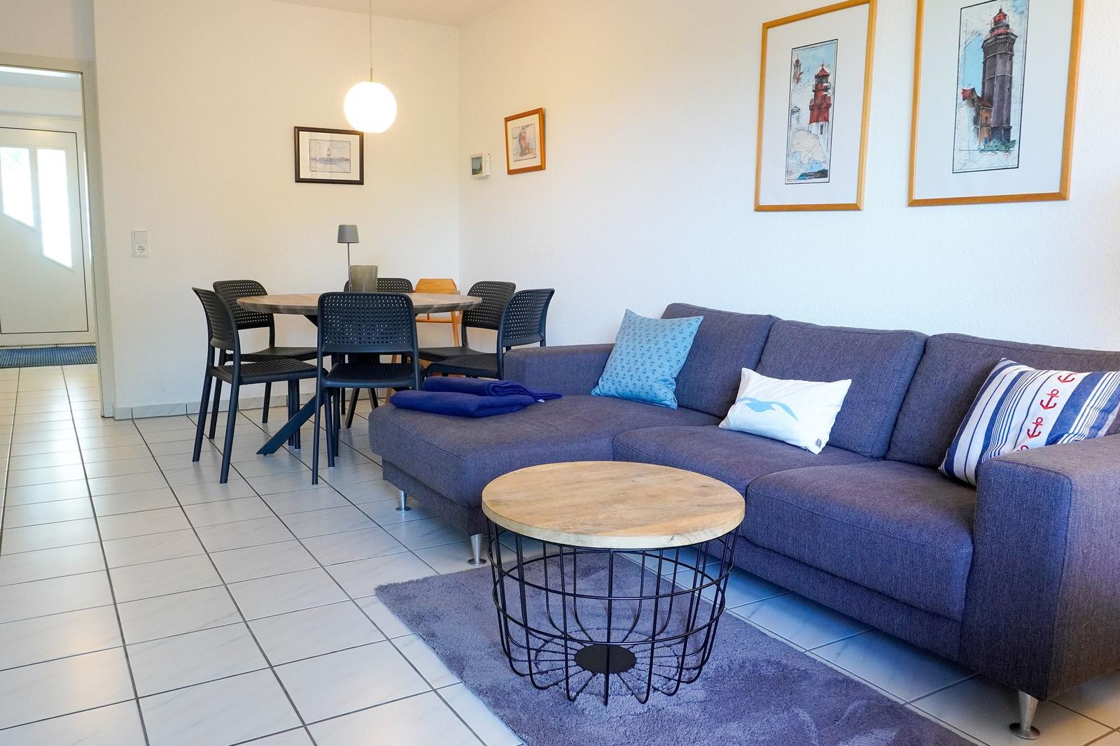 Ein Wohn- und Essbereich mit Sofa, Tisch und Stühlen sowie Wandbildern.