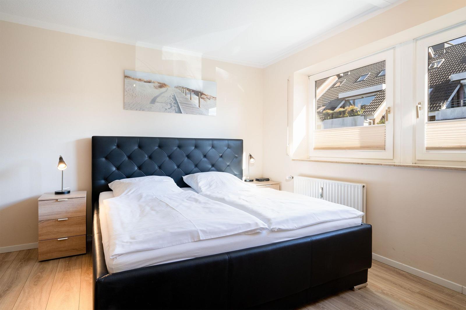 Schlafzimmer mit Doppelbett, Nachttischen und Fensterblick.