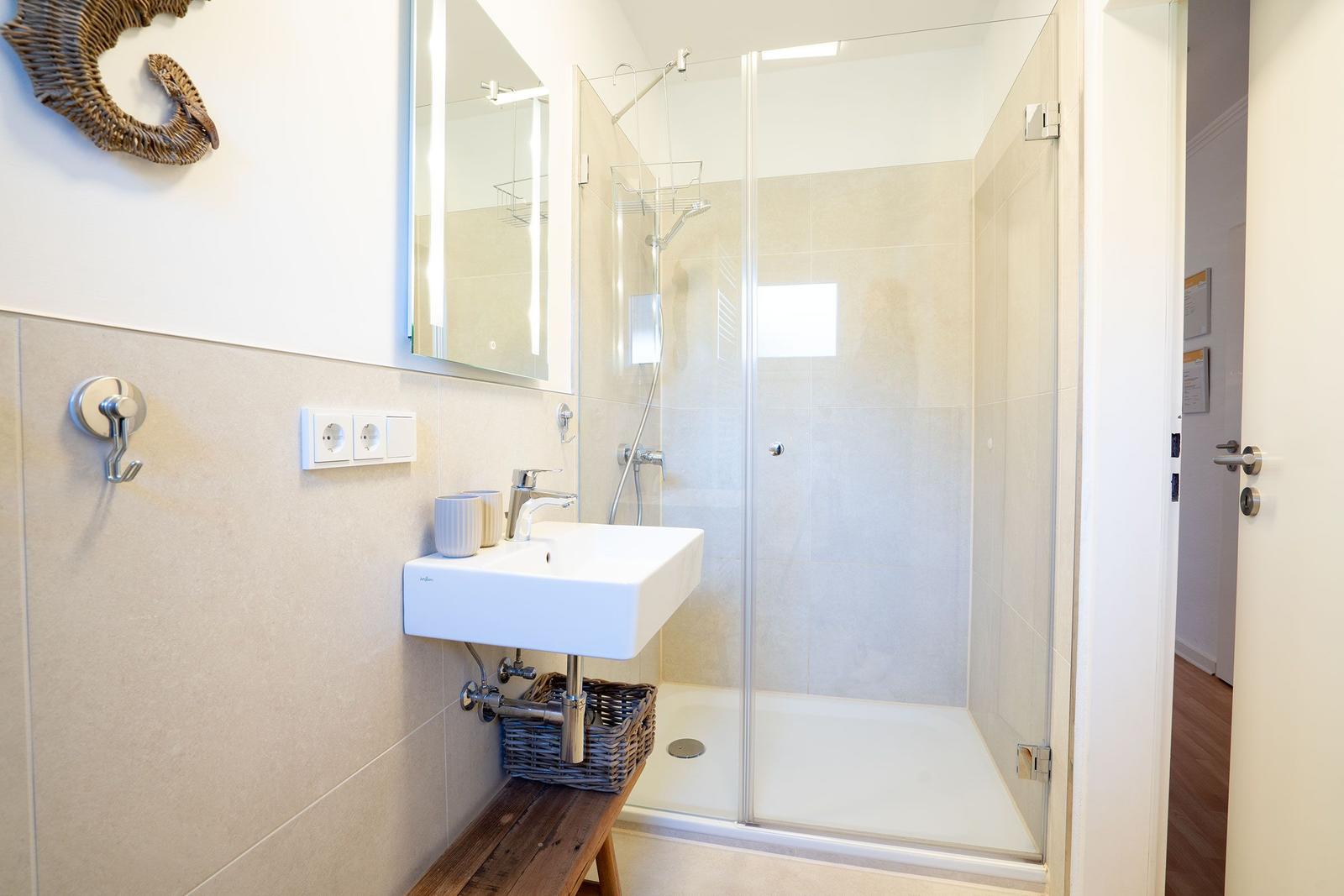 Badezimmer mit Dusche, Waschbecken und Spiegel.