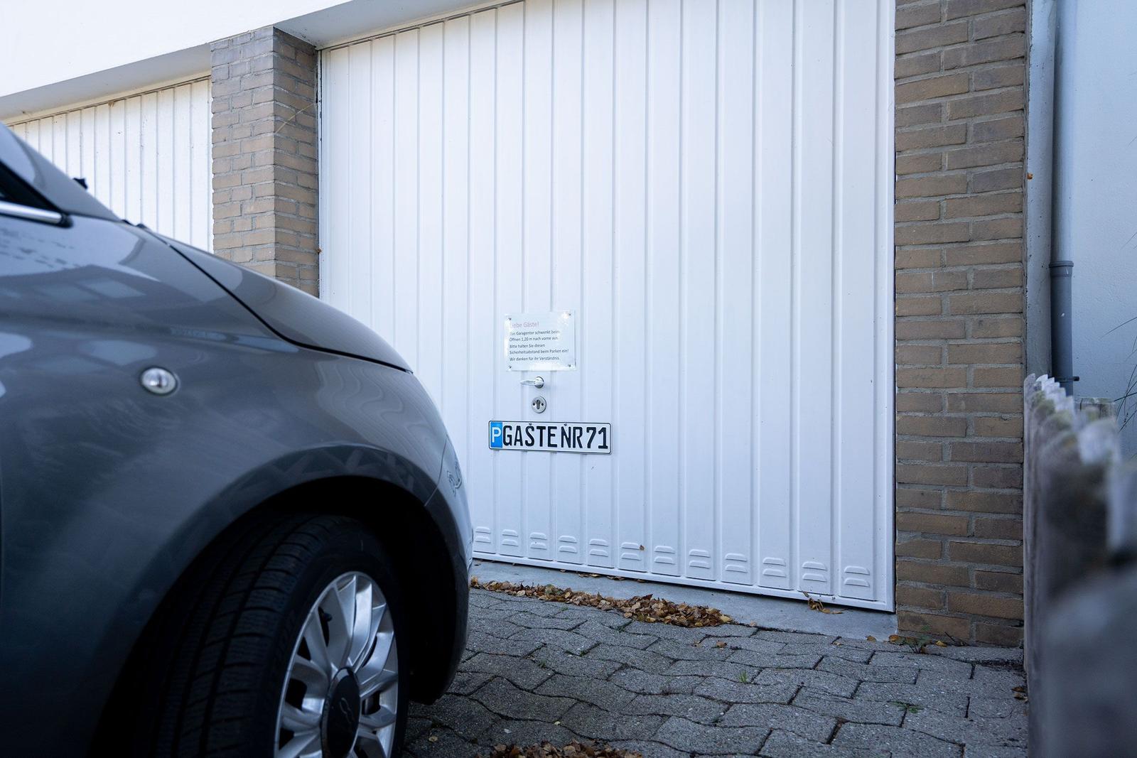 Gastegarage mit Parkplatzschild und weißer Tür. Ein Auto steht vor der Tür.