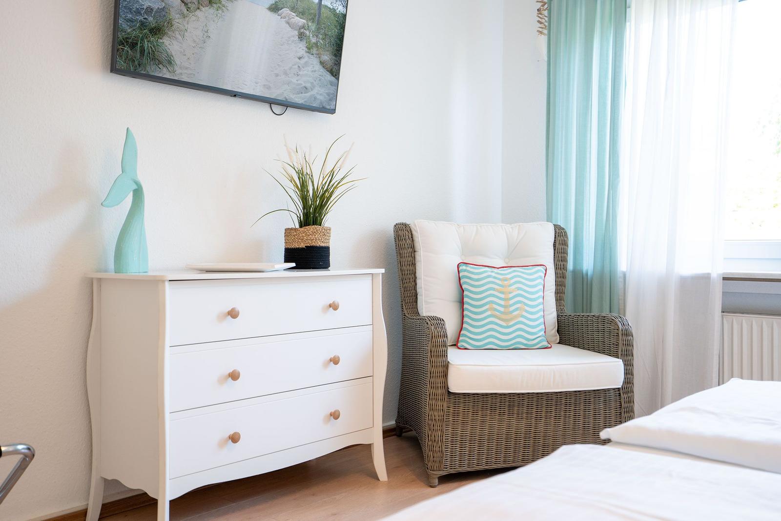 Ein Zimmer mit einem weißen Schrank, einem Stuhl und einem Bett.