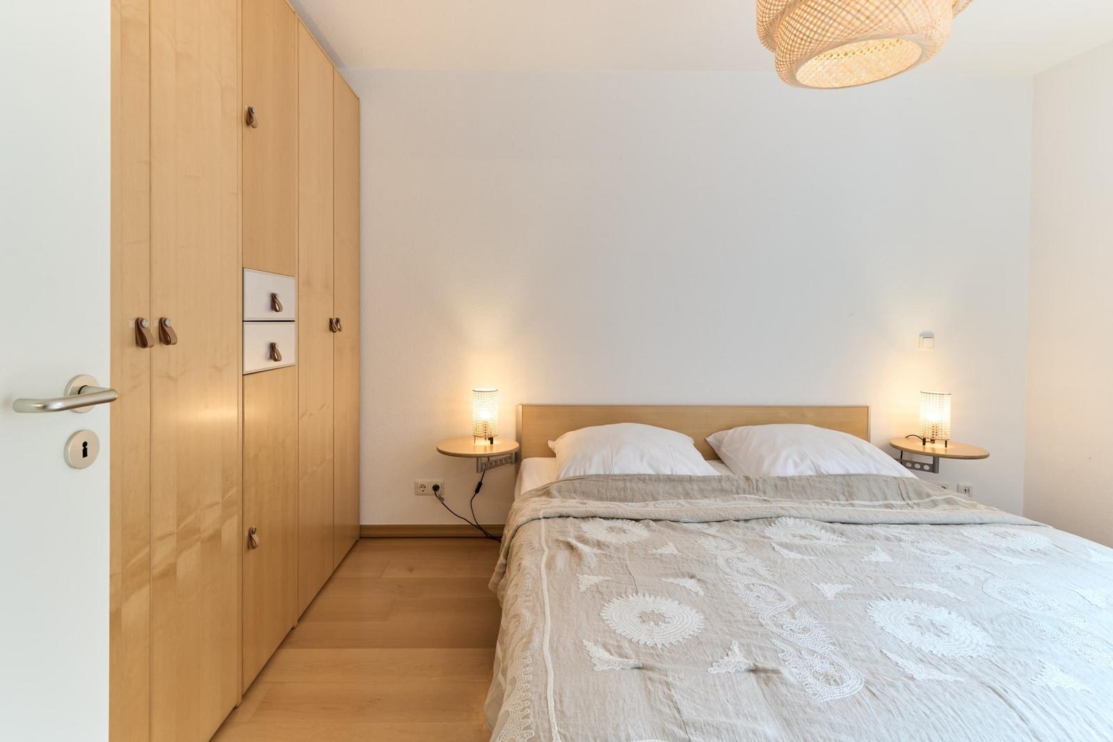 Schlafzimmer mit Bett, Nachttischen und Holzschrank. Deckenleuchte und Beleuchtung.