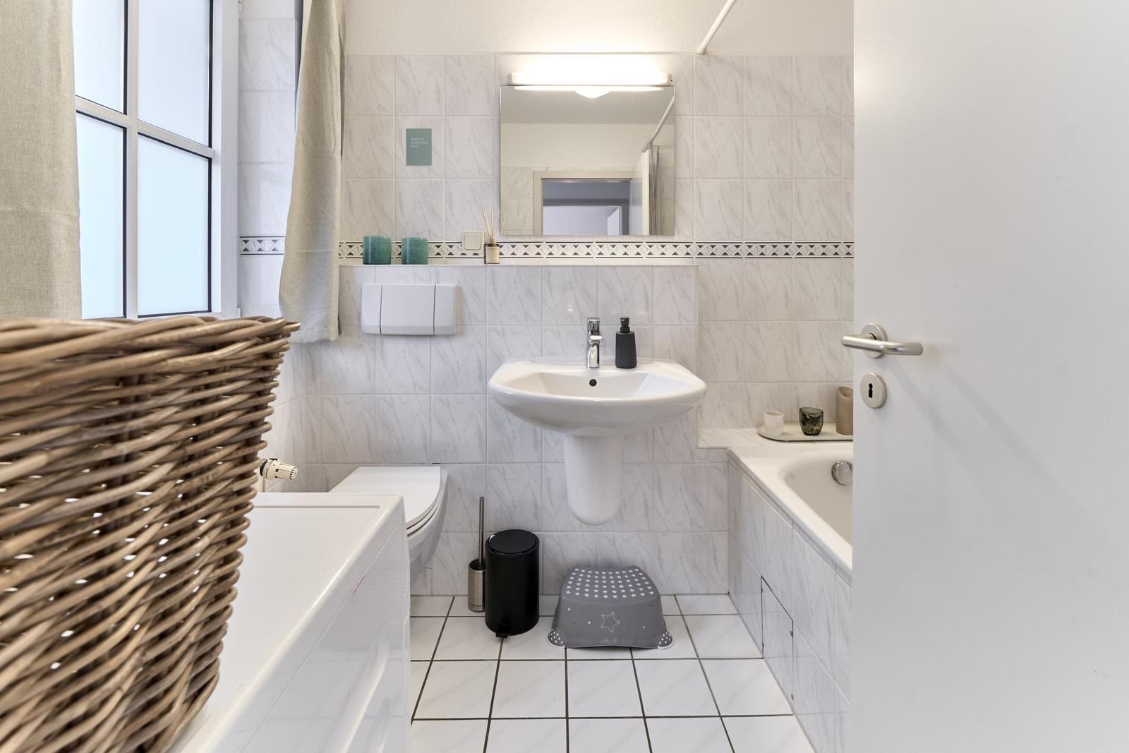Badezimmer mit Waschbecken, Badewanne, Toilette und Fenster.