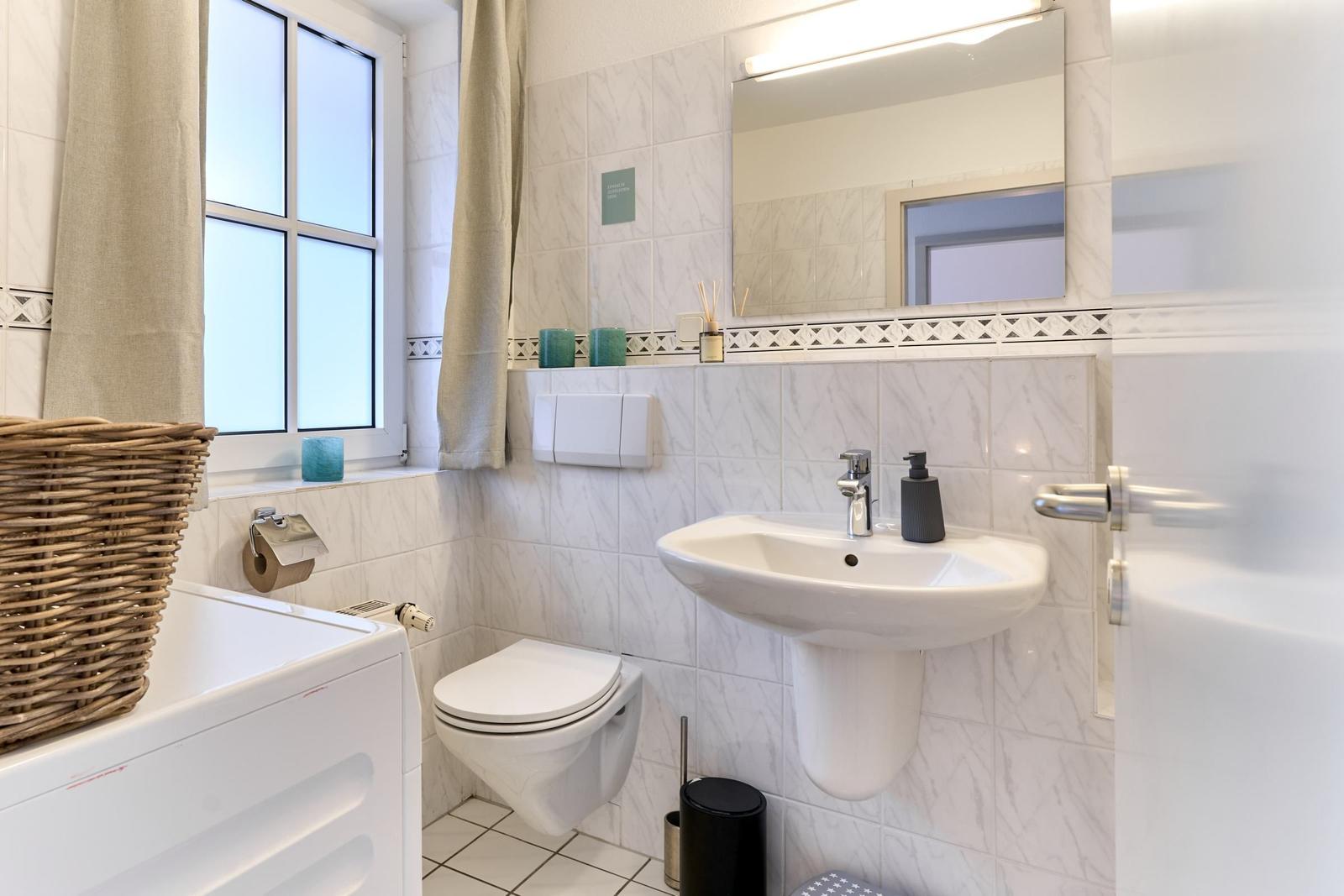Badezimmer mit Waschmaschine, Toilette und Waschbecken.