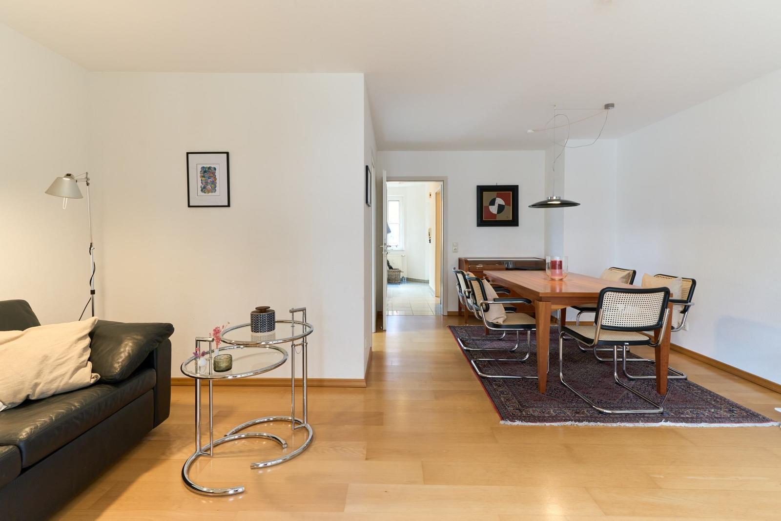 Wohn- und Essbereich mit Holzboden, Sofa, Tisch und Stühlen.