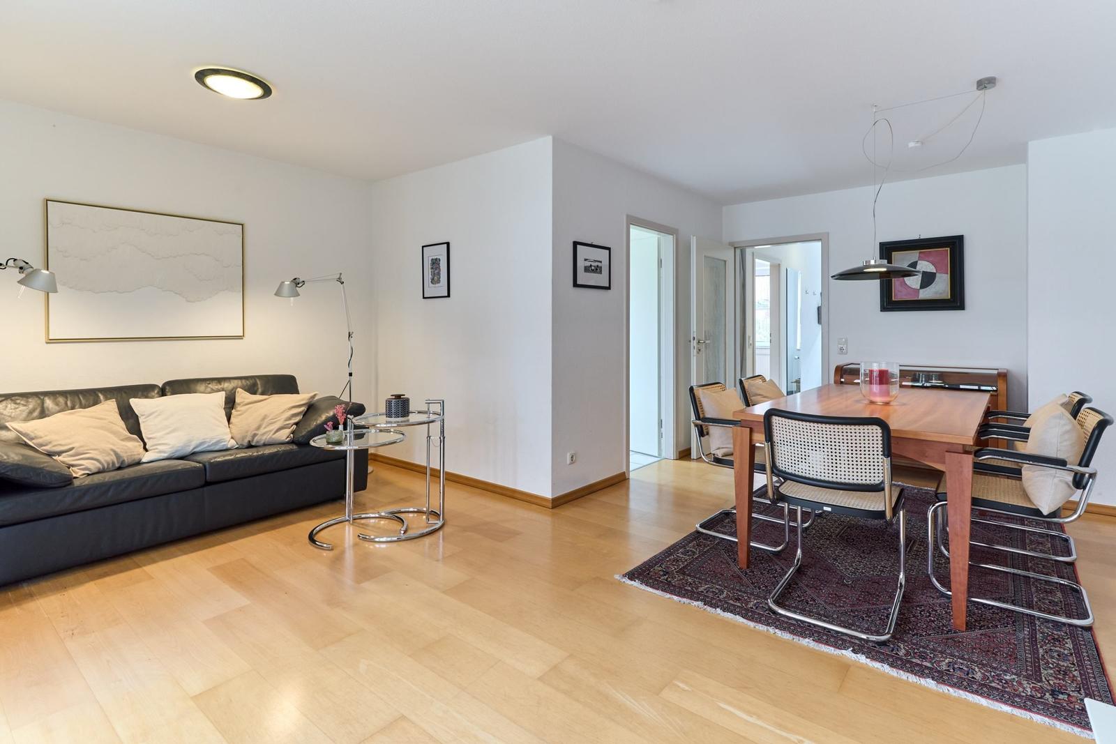 Wohn- und Essbereich mit Sofa, Esstisch und Holzboden.