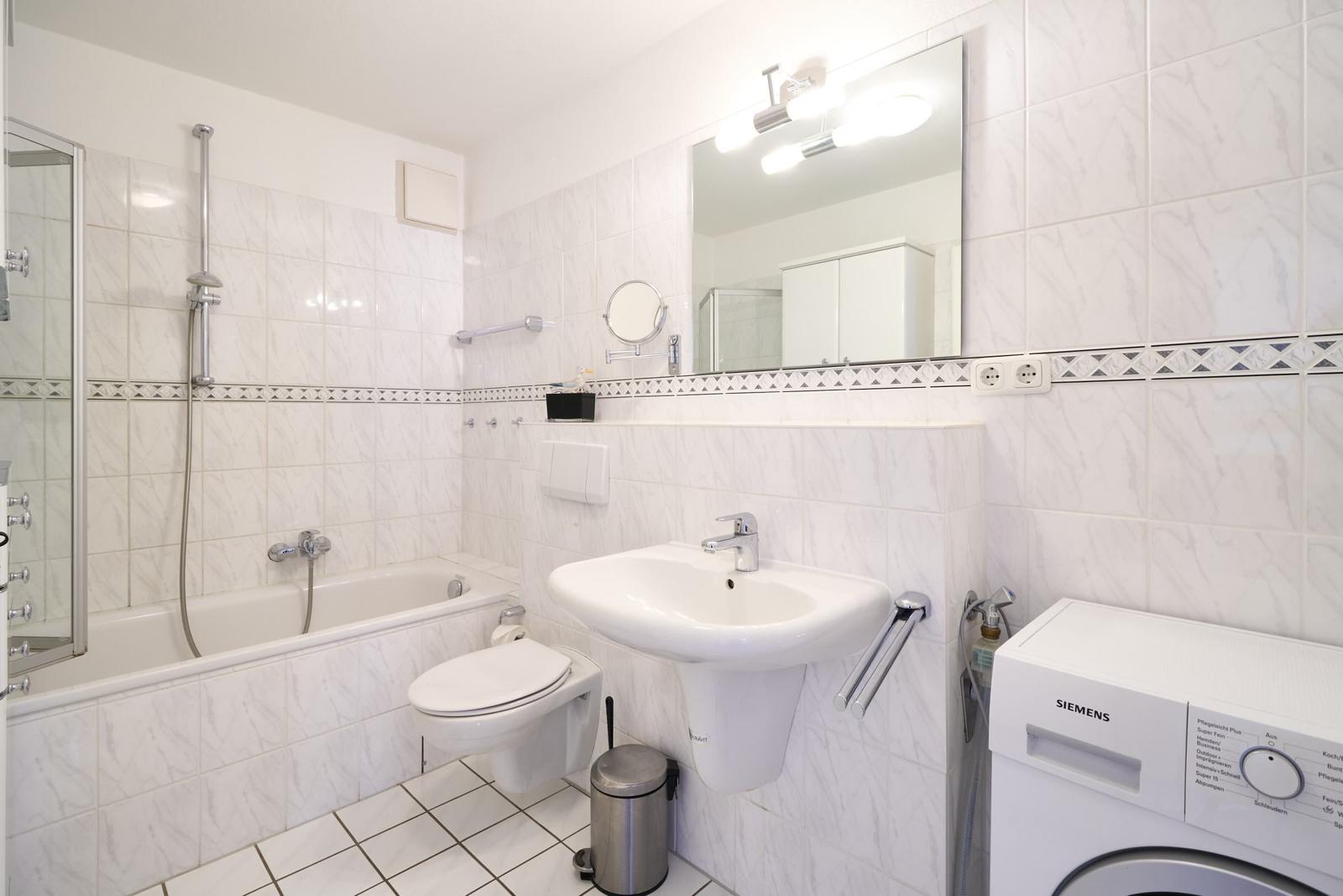 Badezimmer mit Badewanne, WC, Waschbecken und Waschmaschine.