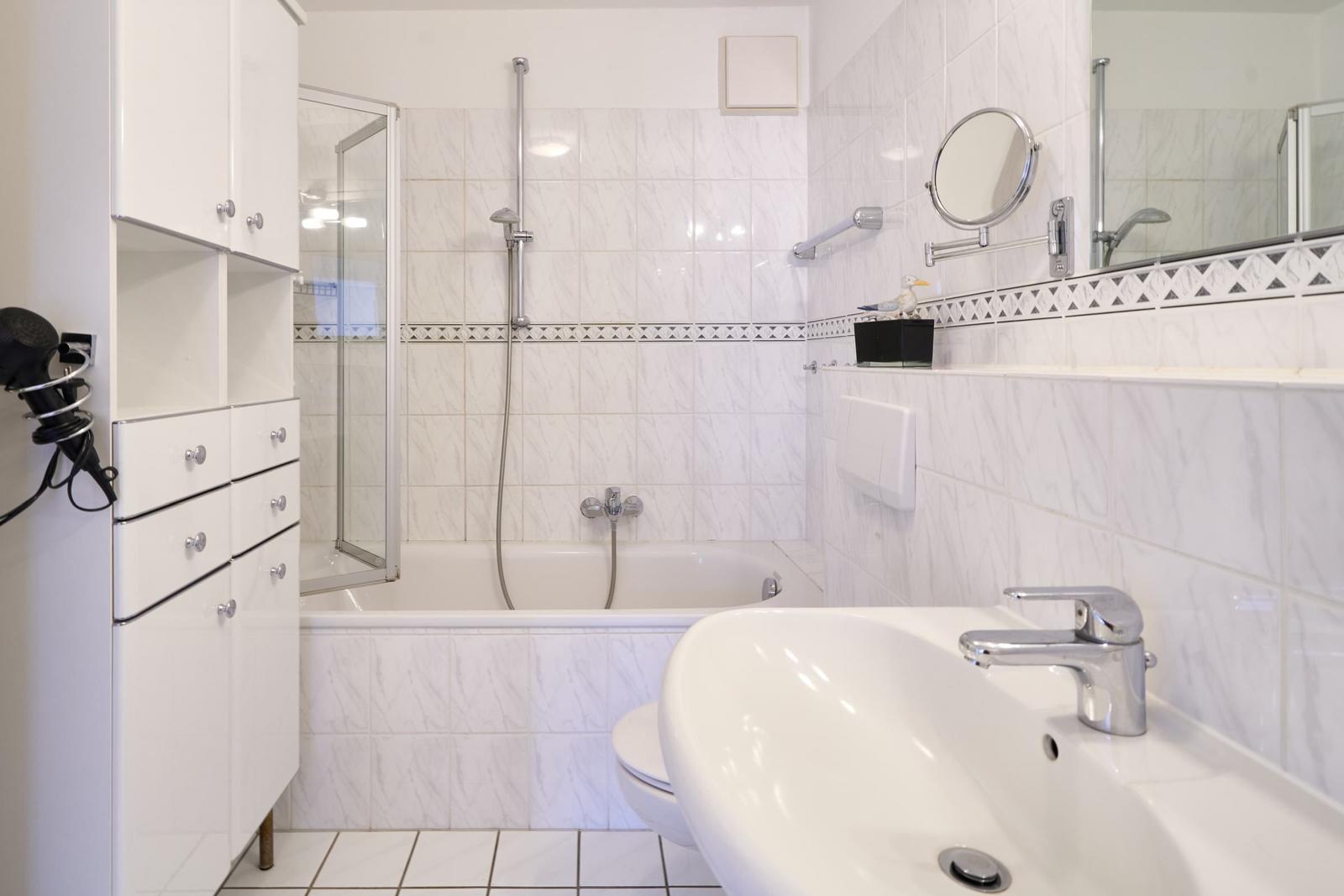 Badezimmer mit Badewanne, Dusche, Waschbecken und Spiegel.