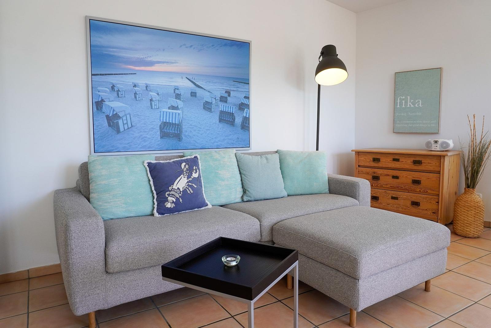 Ein Wohnzimmer mit grauem Sofa, Kissen und einem großen Bild an der Wand.