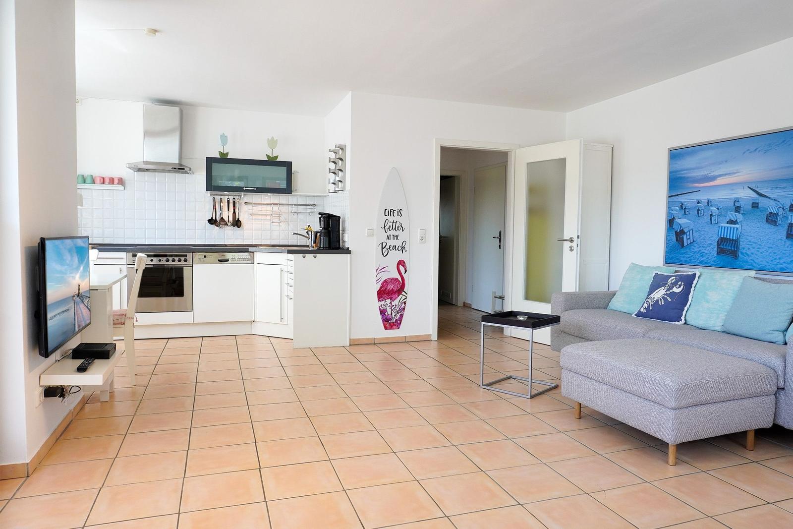 Wohnung mit Küche, Wohnzimmer und Surfbrett an der Wand.