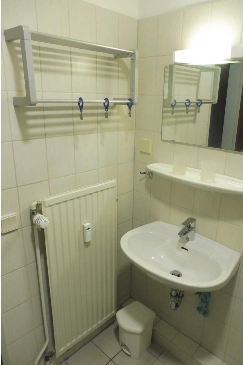 Badezimmer mit Waschbecken, Spiegel, Handtuchhalter und Heizkörper.