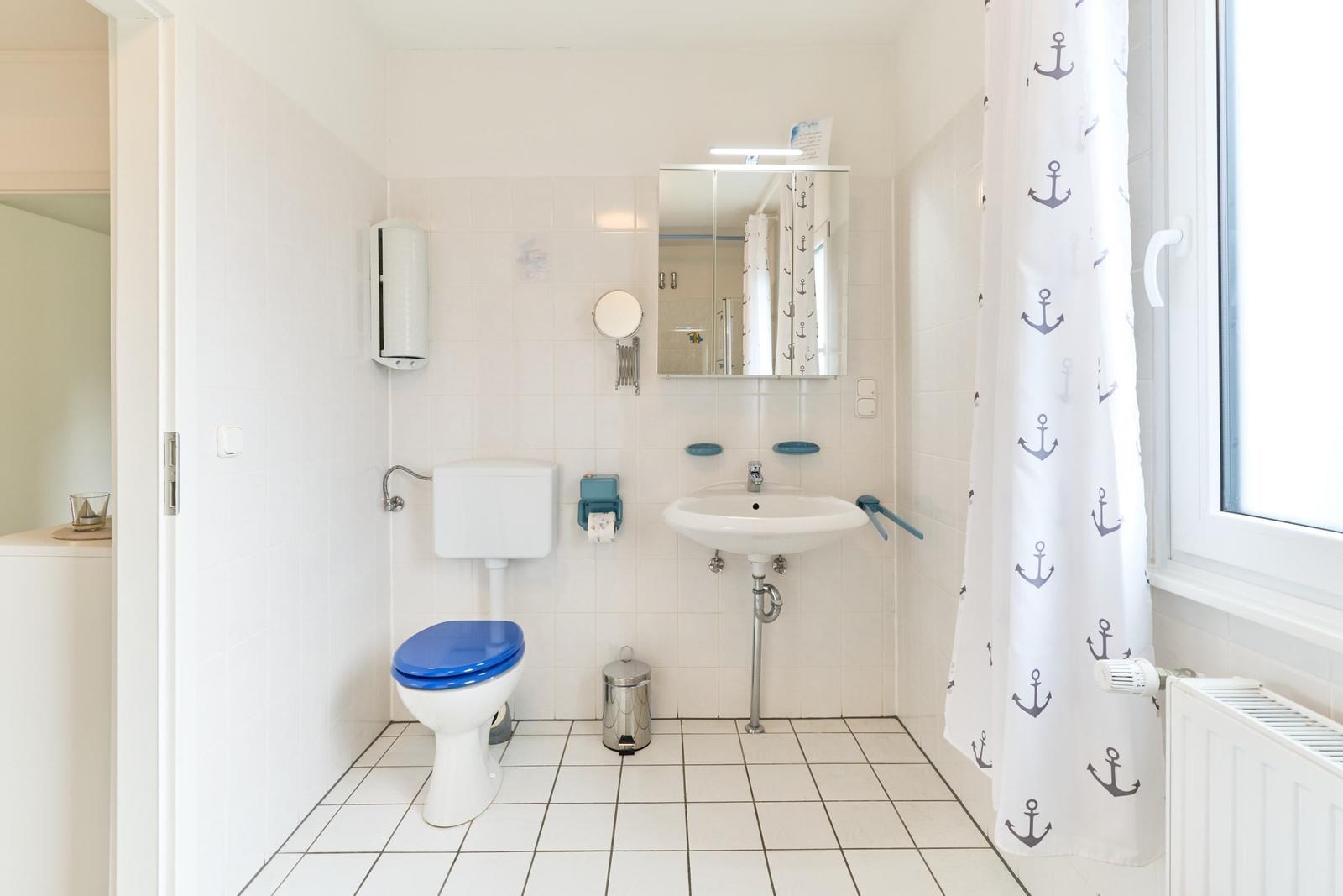 Badezimmer mit Toilette, Waschbecken und Duschvorhang mit Ankern