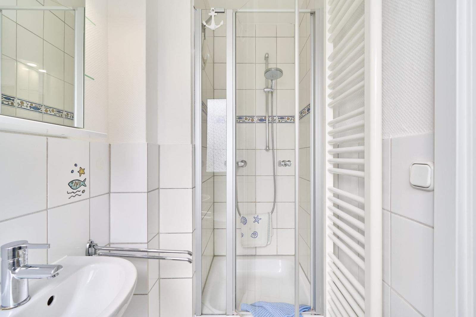 Badezimmer mit Dusche, Waschbecken und Heizkörper