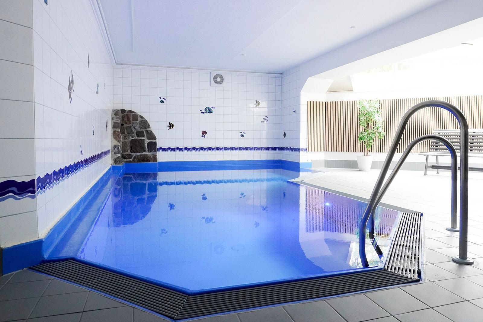 Innenpool mit blauer Wandgestaltung und Metalltreppe