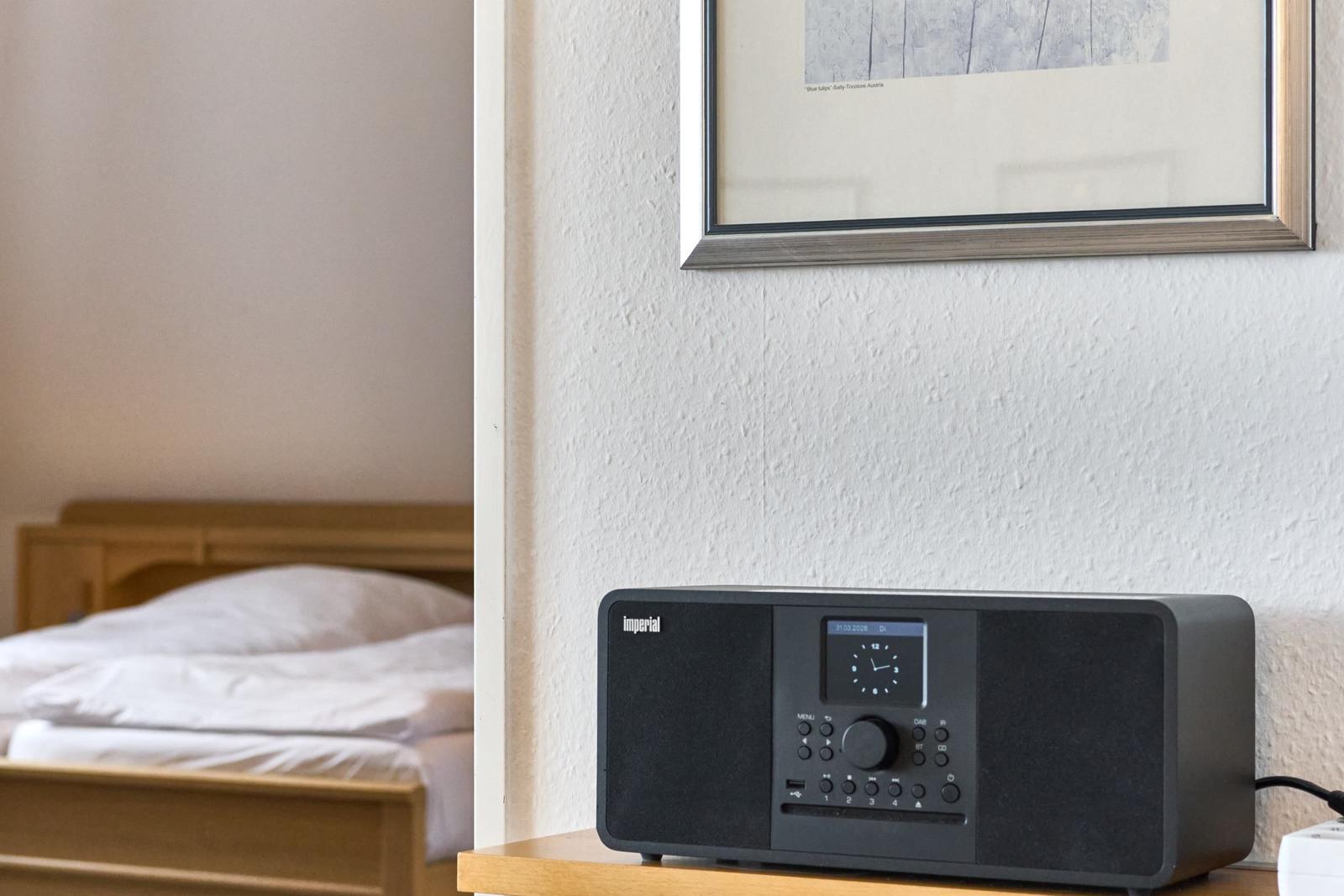 Schwarzes Radio auf Nachttisch neben Bett und Wandbild